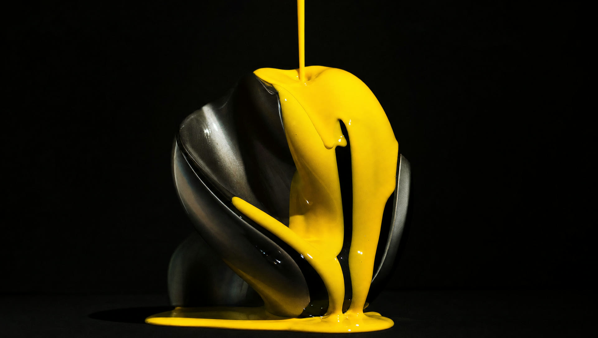Vivid yellow paint pouring over a sculptural form