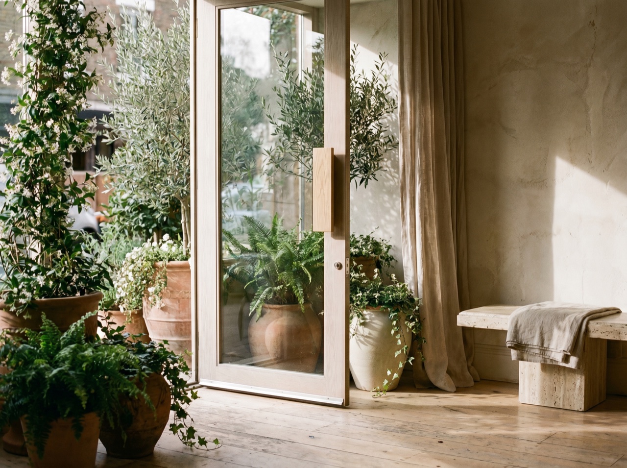 A sunlit salon entrance framed by soft greenery