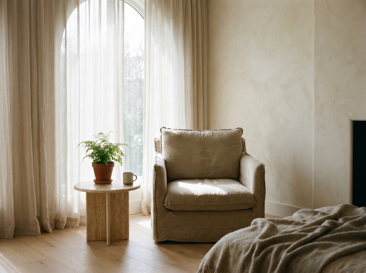 A soft armchair beside a window with gentle daylight