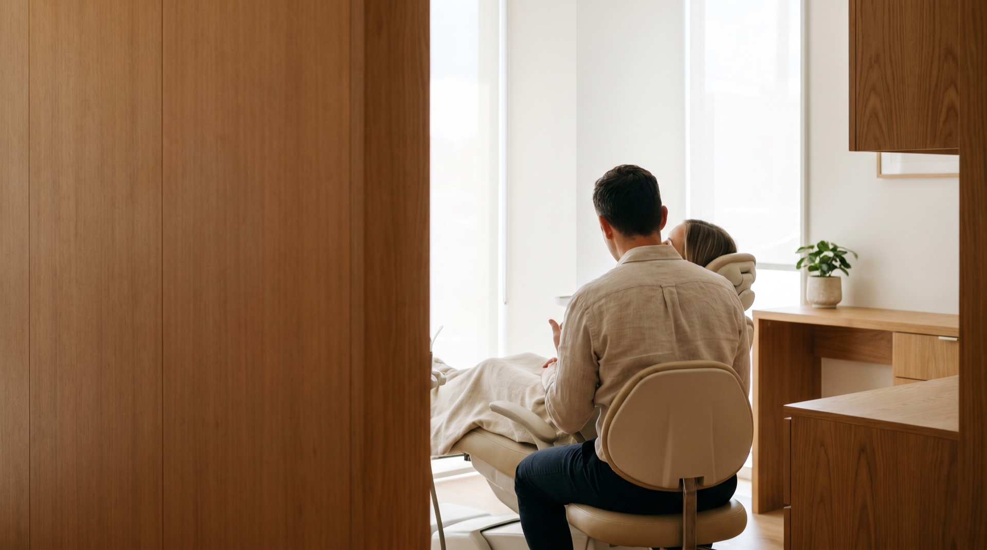 A calm, warm modern dental treatment room in soft daylight
