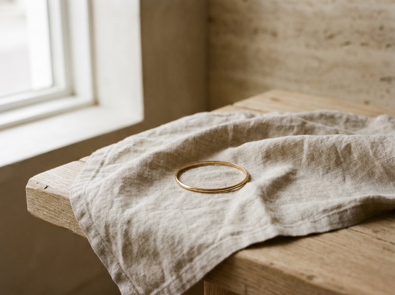 A fine bracelet resting on a folded cloth on pale oak